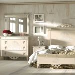 Dormitorio clásico color beige con mesitas de noche, banqueta, cómoda y cabecero decoradas a juego. Dormitorio clásico color beige con mesitas de noche, cómoda y cabecero decoradas a juego.