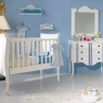 Dormitorio vintage con cuna de madera y cómoda en color blanco con líneas azules. Dormitorio vintage con cuna de madera y cómoda en color blanco con líneas azules.