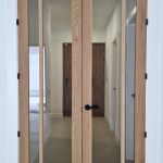 Puerta doble acristalada fabricada en madera maciza de roble con herrajes negros Puerta doble acristalada fabricada en madera maciza de roble con herrajes negros