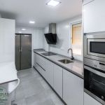 Cocina blanca. Puerta laminada. Tirador Gola. Electrodomésticos inox y negros. Cocina-blanco-brillo-gola-silestone-gris-oscuro
