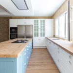 Cocina en forma de L con isla central en color blanco y azul Cocina en forma de L con isla central en color blanco y azul