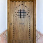 Portón de entrada de madera maciza fabricado a medida. Una hoja + fijo superior. Ventanuco abatible con reja. Herrajes negros. Puerta-entrada-rustica-clavos-herrajes-negros-ventanuco